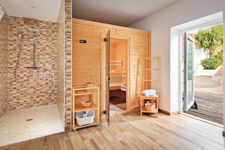 Sauna finlandesa de madera con ducha de lluvia de mosaico y acceso directo al jardín en el Cortijo El Sarmiento – refugio de bienestar en Mojácar