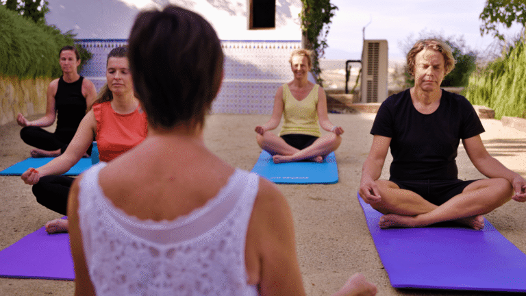 Huéspedes meditando en una clase de yoga guiada al aire libre en el Cortijo El Sarmiento – mindfulness y tranquilidad bajo el sol andaluz